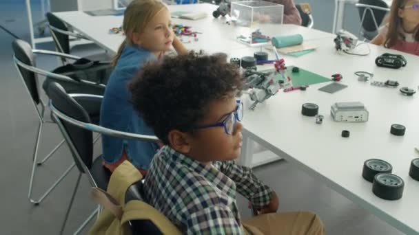 ロボットサイエンスのクラスでブロックやレンガを構築し オフスクリーン教師に耳を傾けるカジュアルな服で多様な若い子供たちのハイアングル中型ショット — ストック動画
