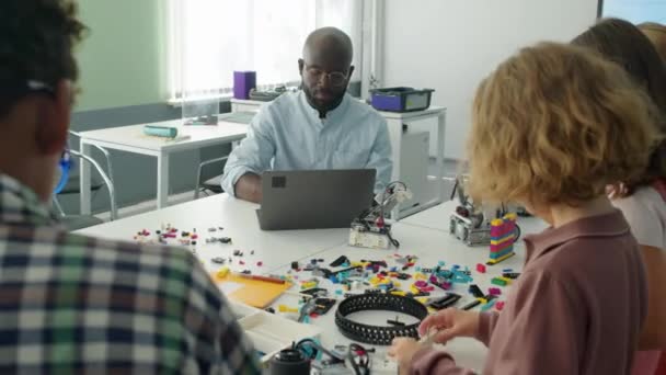 Średnie Ujęcie Ramieniu Afroamerykańskiego Nauczyciela Pracującego Laptopie Podczas Gdy Grupa — Wideo stockowe