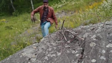 Yakacak odun tabakası, taştan gelen melez genç bir erkek turist tarafından alınıyor.