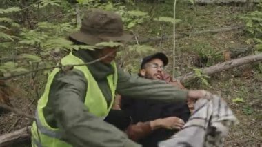 Genç kadın melez kurtarıcının, erkek melez, yorgun turisti battaniyeyle örttüğü orta boy bir fotoğraf.