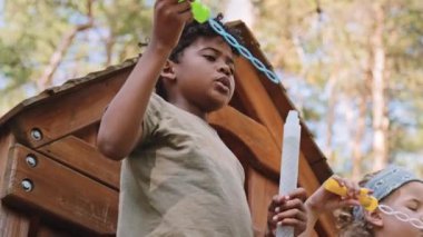 Afrika kökenli Amerikalı ve Kafkas ilköğretim çağındaki çocukların ağaç evde sabun köpüğü yapmaları sağa doğru dönüyor.