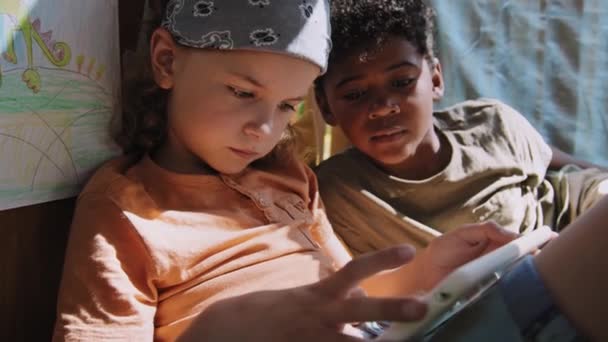 两名非裔美国人和白人小学生白天在树屋玩平板游戏的慢镜头 — 图库视频影像