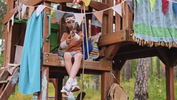 Tiro Completo Niño Edad Elemental Caucásico Sentado Árbol Fingiendo Disparar — Vídeos de Stock