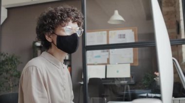 Maske takan ve gündüz vakti bilgisayarla çalışan beyaz bir kadının orta boy fotoğrafı.