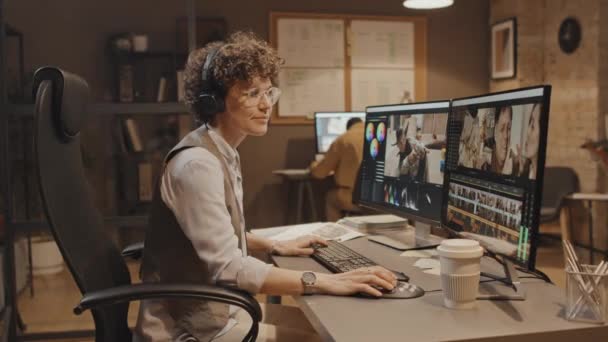 白种人年轻女子坐在办公桌前与计算机一起工作 转身看着相机的慢幅肖像 — 图库视频影像
