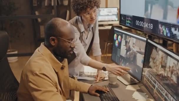 白种人女制作人斜视镜头 看着大屏幕和小屏幕 向非洲裔美国男性同事推荐项目 — 图库视频影像