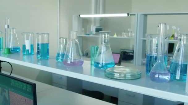 没有人把注意力集中在装有五颜六色液体的瓶子的化学实验室架子上 — 图库视频影像