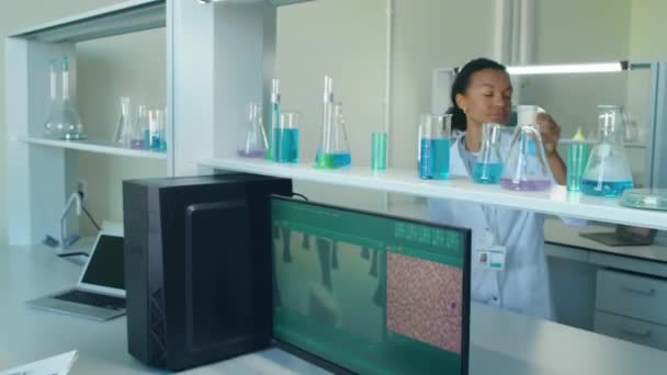 Biracial 실험실 선반에서 플라스크를 세포와 화면을 동료에서 — 비디오