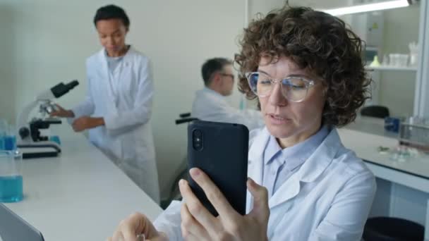 白种人女化学家中特写在实验室视频通话中谈论研究和用液体显示试管 — 图库视频影像