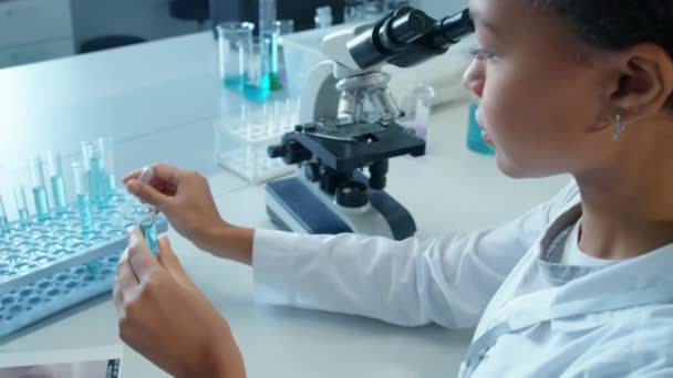 白种人女实验室女员工坐在实验室桌上 用试管中的滴注液抽取样品时的肩后背照 — 图库视频影像