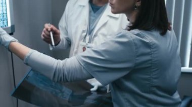 Yetişkin erkek ve genç kadın doktorların seçmeli odak noktası röntgen taraması görüntülerini okumak için ofiste durmaları.