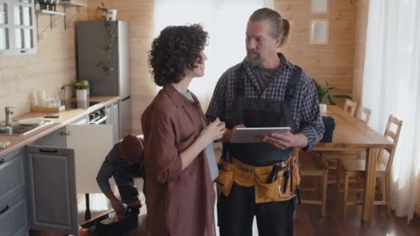 Mature Caucasian Repairman Holding Digital Tablet Female Client Standing Kitchen — Stock Video