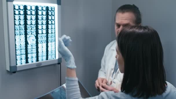 Profesjonalni Pracownicy Medyczni Czytający Zdjęcia Rentgenowskie Pacjentów Umieszczone Lightbox Omawiający — Wideo stockowe