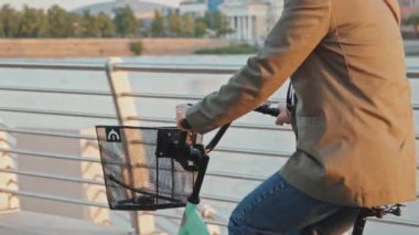 Sabahları nehir kıyısında bisiklete binen tanınmayan bir kadının orta boy görüntüsü.