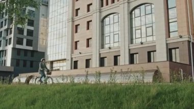 Kafkasyalı kadın ofis çalışanı, sabahları bisiklet sürerken geniş açıdan görülüyor.