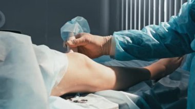 Ameliyathanede, ameliyattan önce hastaların dizlerinin ultrasonografisini yapan tanınmamış bir erkek tıp uzmanı.