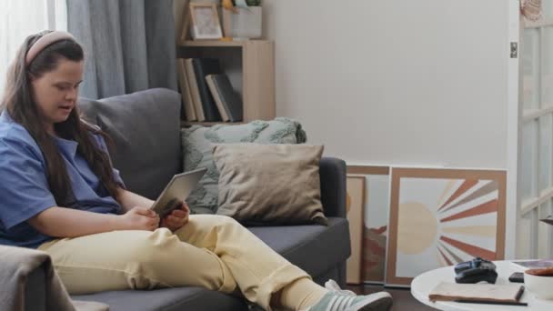 Снимок Молодой Девушки Синдромом Дауна Сидящей Диване Гостиной Видеозвонком Цифровой — стоковое видео