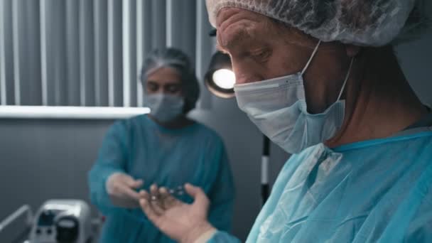 Selektywne Skupienie Się Asystencie Dającym Przyrząd Dojrzałemu Lekarzowi Podczas Operacji — Wideo stockowe