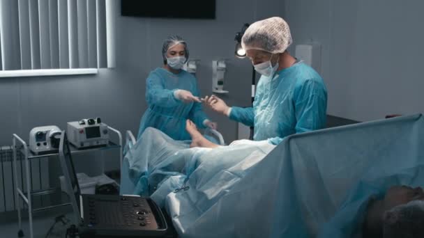 Specjalista Medyczny Pracujący Sali Operacyjnej Wykonujący Operacje Kolana Dla Pacjentki — Wideo stockowe