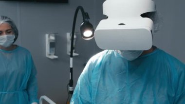 Modern hastanedeki ameliyathanede hastayla çalışırken erkek cerrahın VR kulaklığı kullanması.