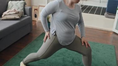 Down sendromlu beyaz bir kadının evde esneme egzersizi yaparken elde çekilmiş fotoğrafı.