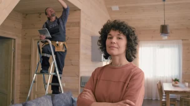 具有卷发的白人妇女的肖像站在现代住宅的客厅里 而专家设置了智能家居系统 — 图库视频影像