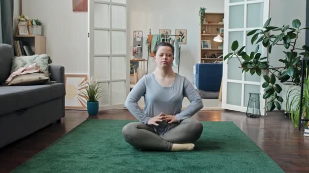 Sendromlu Modern Beyaz Kadın Oturma Odasında Halıya Oturmuş Yoga Yapıyor — Stok video