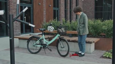 Kafkasyalı bir kadının şık bir kıyafet giyip dışarıda bisiklet lastiklerini şişirdiği uzun bir çekim.