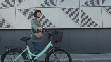 Kafkaslı modern beyaz iş kadını bisikletle sokakta yürürken Dolly 'nin fotoğrafı.