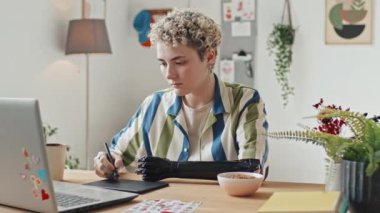 Özürlü modern Z neslinin portresi dizüstü bilgisayarın önünde grafik tableti kullanarak resim çiziyor.