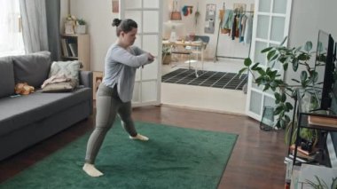 Down sendromlu modern genç bir kadının oturma odasında yoga yaparken ki görüntüsü.