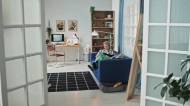 Engelli modern genç bir kadının dijital tabletle internette sörf yapıp koltukta dinlenmesi.