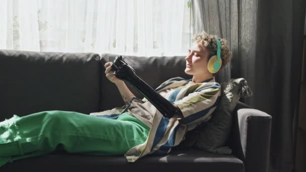 Chica Moderna Gen Con Discapacidad Usando Auriculares Relajándose Sofá Sala — Vídeos de Stock