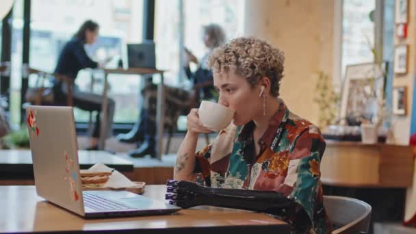 现代咖啡店中戴着假臂 身穿时髦衬衫 享受咖啡的年轻女性的选择性聚焦镜头 — 图库视频影像