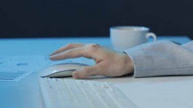 Yan görünüş, masa başında oturan bilgisayar faresi ve klavyeyle çalışan kadın sekreterin gece ofiste bir şeyler yazışının görüntüsü.