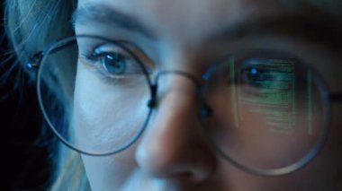 Bilgisayar programında masa başında oturan, ekranın yansıması olan gözlük takan bir kadının aşırı yakınlaşması.