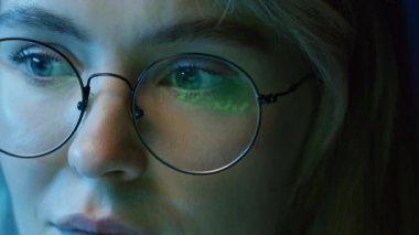 Bilgisayar ekranında kripto grafikleri takip eden, içinde yansıma olan gözlük takan genç bir kadının sol uç noktasında geziniyor.