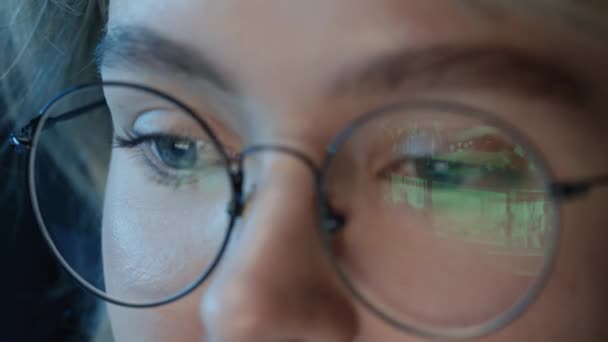 夜に見るためにフィルムを選択するストリームウェブサイトの反射で透明なメガネを着用している女性の極端なクローズアップ — ストック動画
