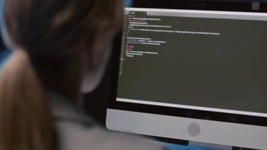 Kadın programcının omzunun üstünden. Masada oturuyor. Geceleri ofiste kod yazıyor.