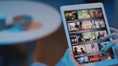 Elinde tabletle ekranda tanımadığımız bir kadının görüntüsünü çekip izlemek için filmi seçiyor.
