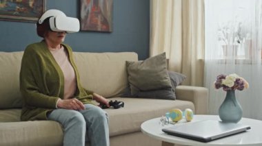 Orta boy beyaz kadın oturma odasında kanepede otururken AR gözlükleri takıp oyun oynadıktan sonra yorgun hissediyordu.
