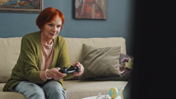 Пэддок Оставил Средний Снимок Возбужденной Пожилой Женщины Играющей Видеоигры Диване — стоковое видео