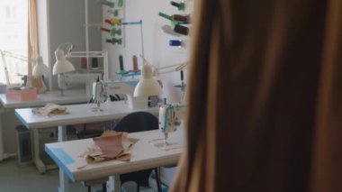 Sabah işe başlamadan önce küçük el sanatları atölyesinde profesyonel dikiş makineleriyle dolu masalar, iplik makaraları ve deri parçaları.