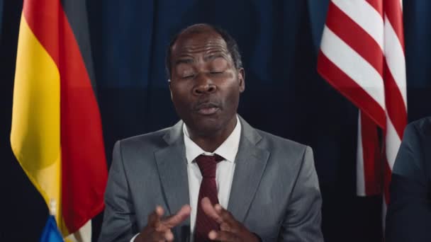 中年アフリカ系アメリカ人政府大臣がスーツを着てトリビューンに座り 国際サミットで現在の議題について感情的なスピーチを行いました — ストック動画