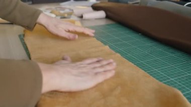 Atölyede çalışırken, beyaz tenli, atölyede deri parçalarını düzleştirirken tanınamaz hale gelen orta yaşlı bir kadının yakın plan fotoğrafları.