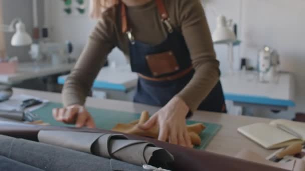 프론에 Craftswoman의 클로즈업 가죽의 테이블에 새로운 핸드백에 가죽의 조각을 부드럽게 — 비디오