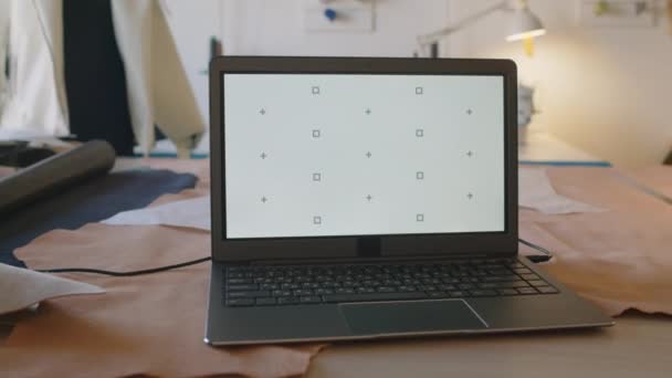 Laptopszámítógép Közelkép Üres Képernyővel Mintázott Vágóasztalon Divatműhelyben Bőrtekercsekkel Papírkivágásokkal Bábukkal — Stock videók