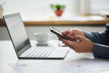 Cep telefonlu genç bayan girişimcinin kamera karşısında otururken çevrimiçi verilere baktığı yakın plan.