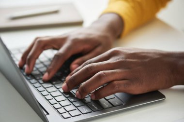 İş ya da okul projesi üzerinde çalışırken dizüstü bilgisayarda yazan genç Afrikalı Amerikalı çalışanın ya da öğrencinin sol eline odaklan