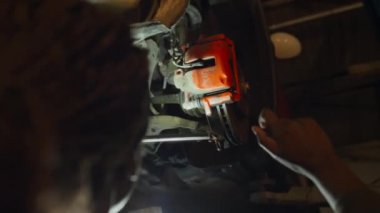 Profesyonel oto tamircisi olarak çalışan genç siyahi bir kadının araba arızası ararken düşük açılı çekimi.